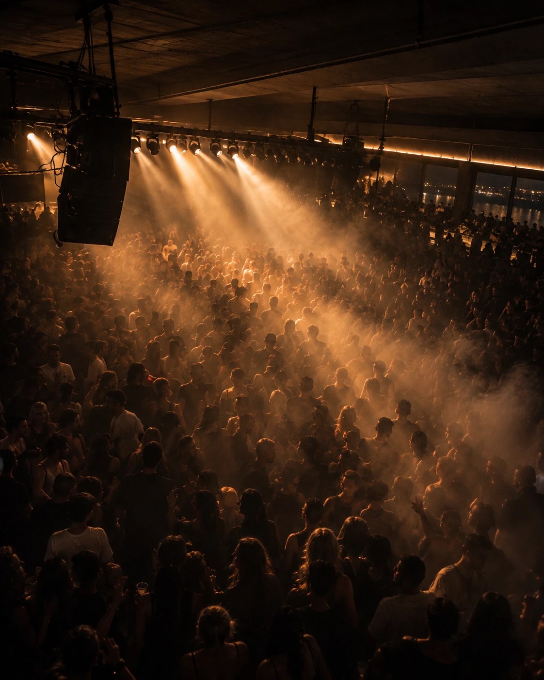 A packed Tropicana dancefloor seen from above, light beams cutting through haze