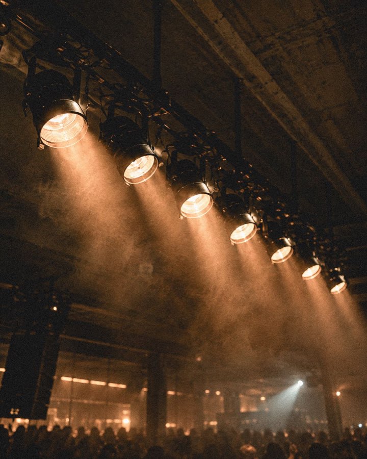 A row of stage lights through haze above the crowd
